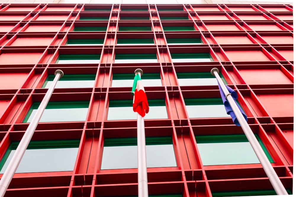 um edifício vermelho e verde com duas bandeiras