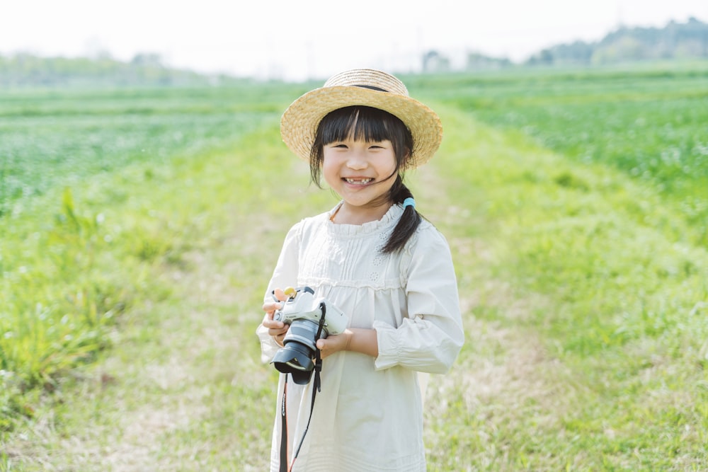 a little girl holding a camera in a field