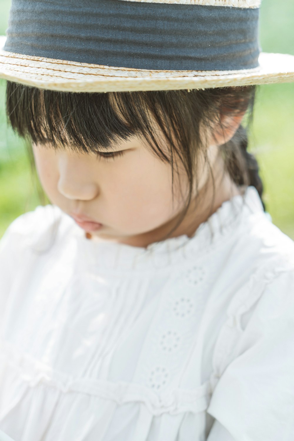a little girl wearing a hat looking at a cell phone