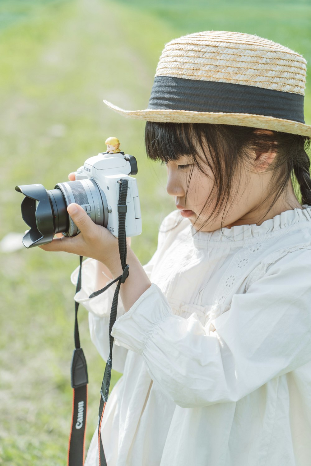 a woman in a white dress and hat holding a camera