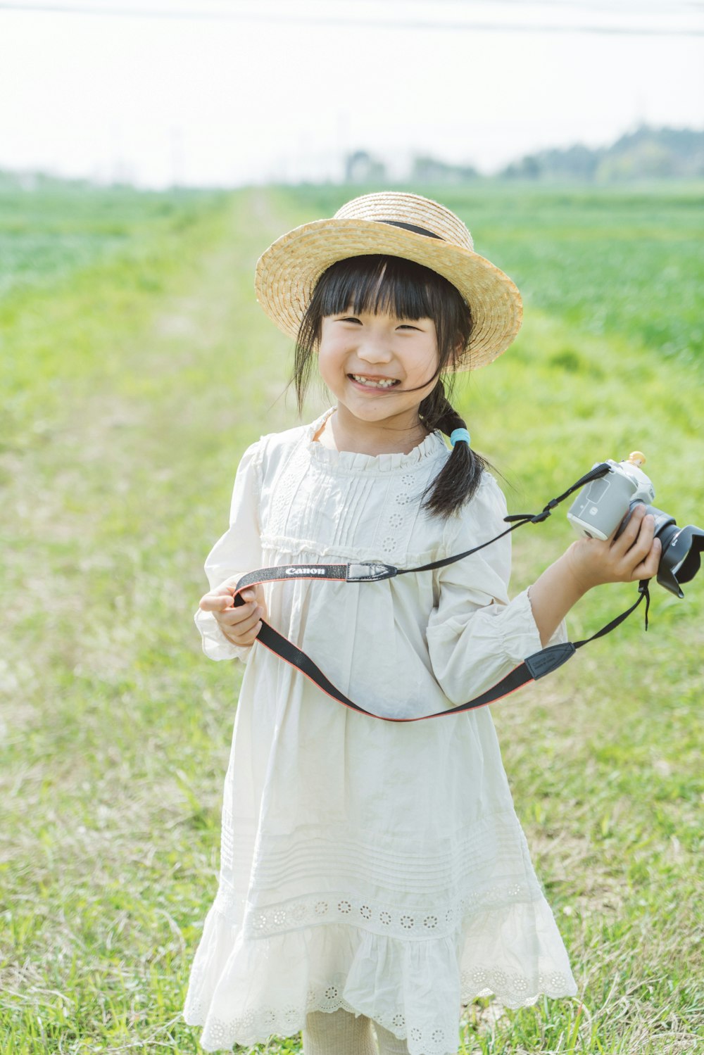 a little girl holding a camera in a field