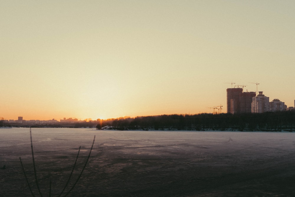 the sun is setting over a frozen lake