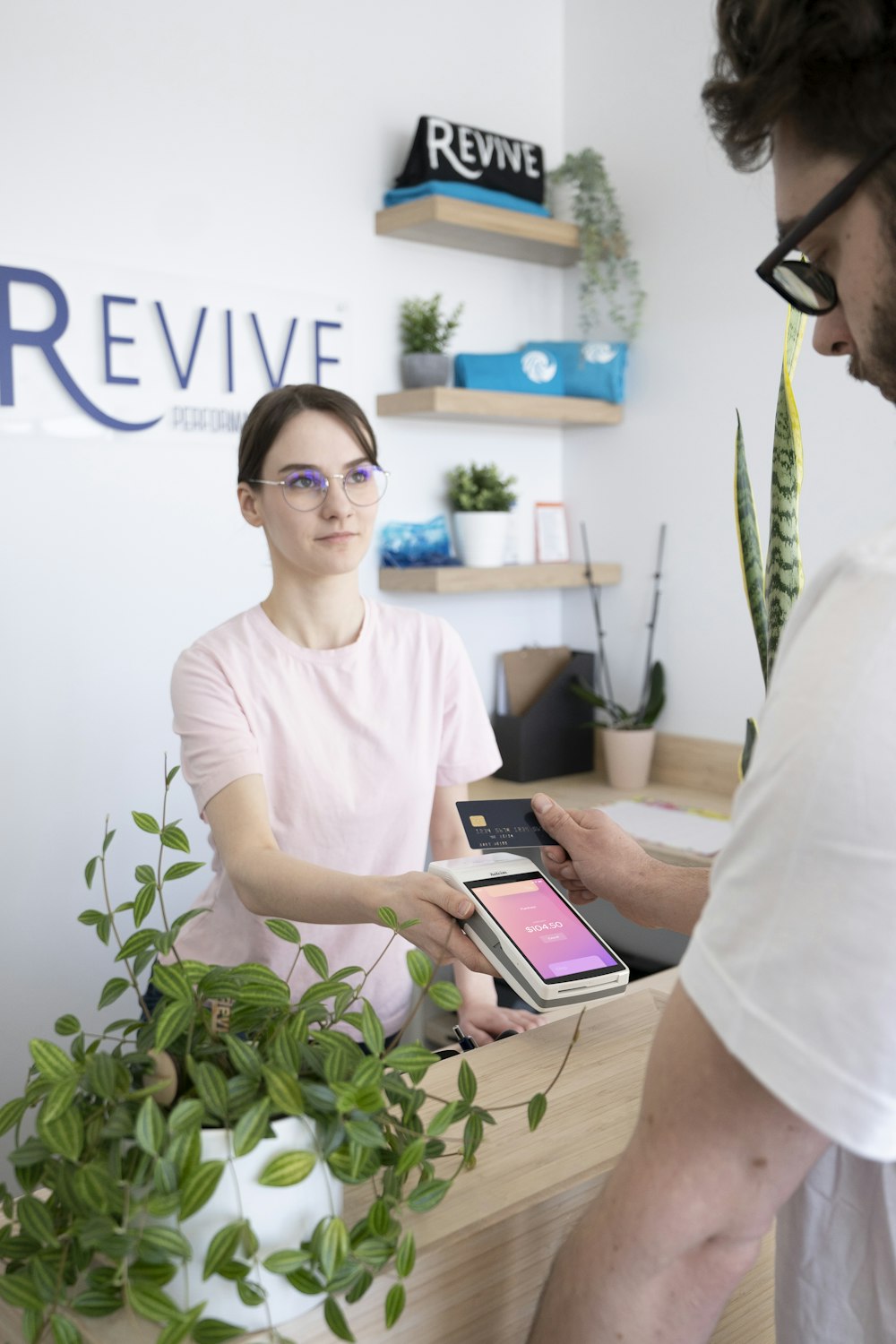 a man and a woman sitting at a desk in front of a plant