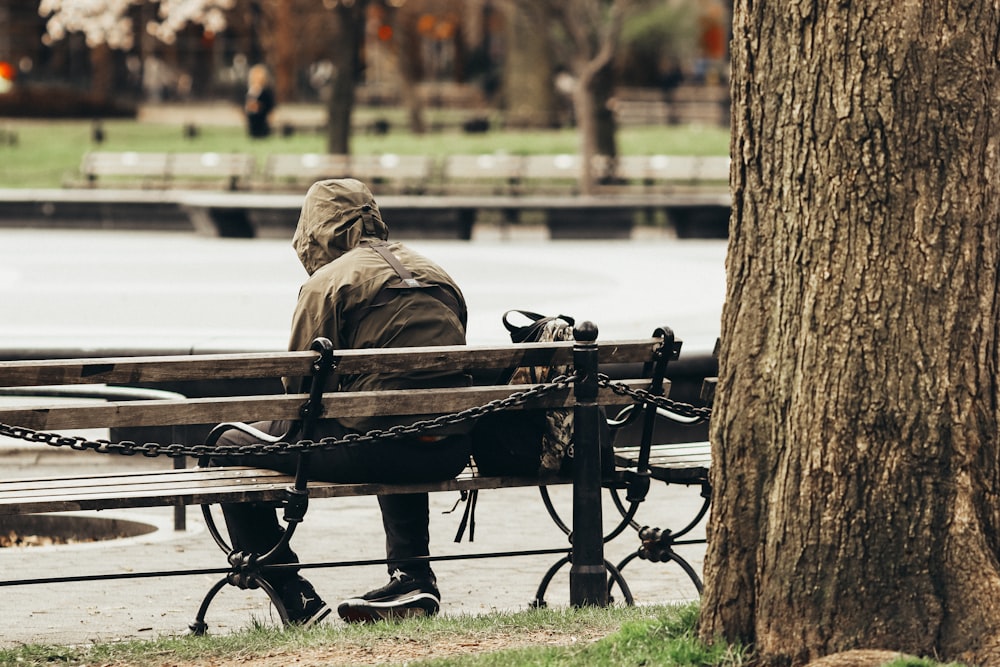 a man sitting on a bench next to a tree