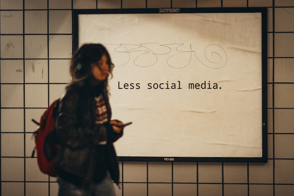 a woman standing in front of a sign that says less social media