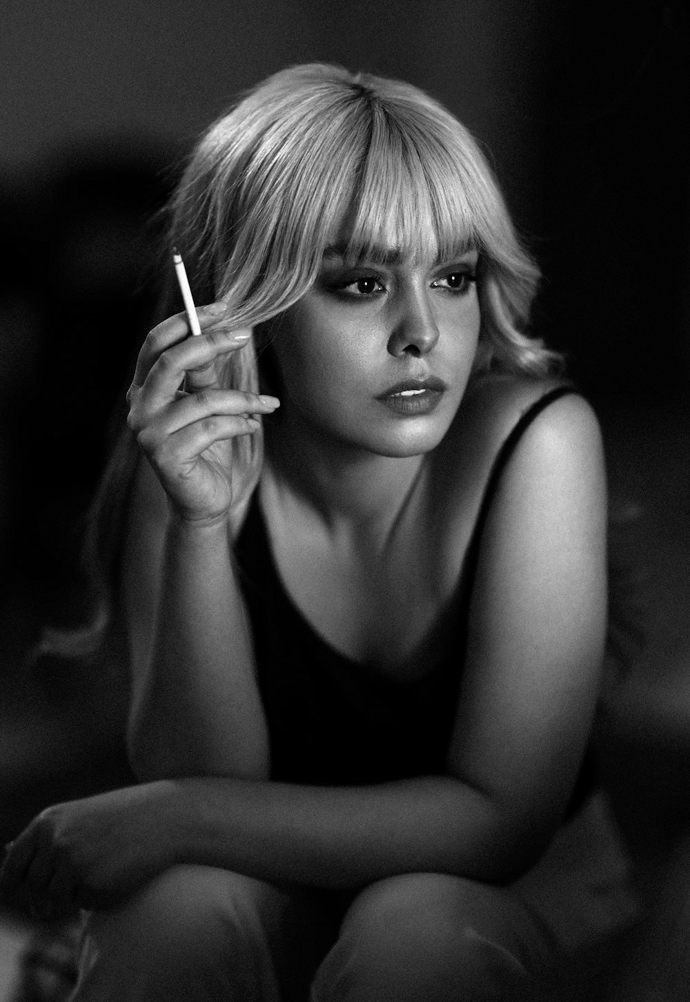 a black and white photo of a woman smoking a cigarette