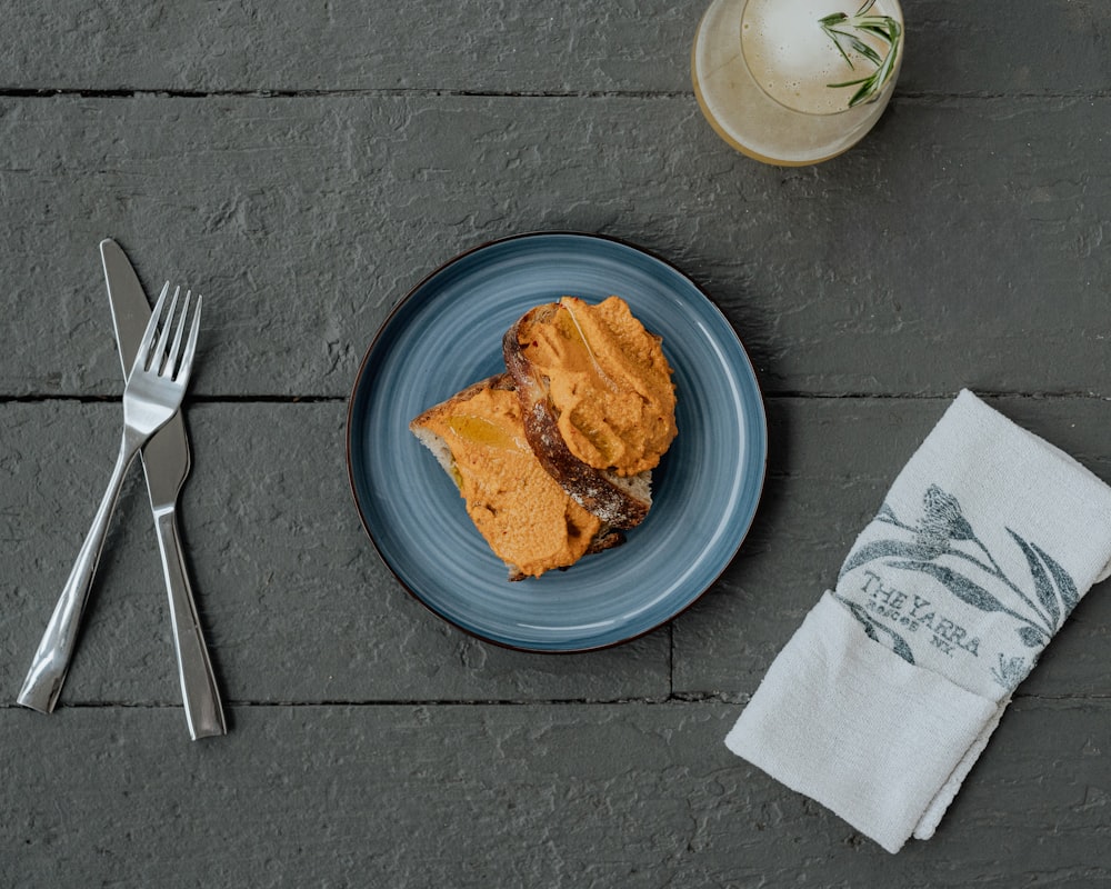 a blue plate topped with a piece of cake next to a fork