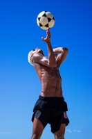 a shirtless man is playing with a soccer ball