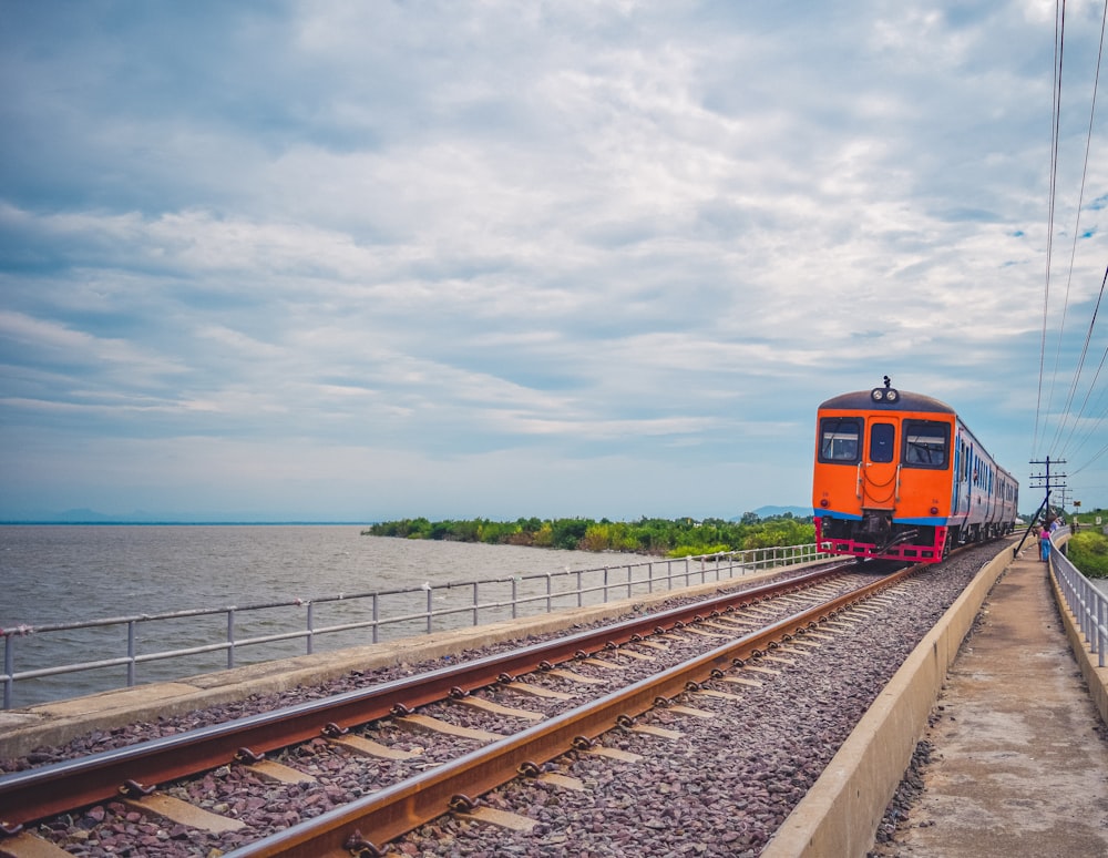 a train traveling down tracks next to a body of water