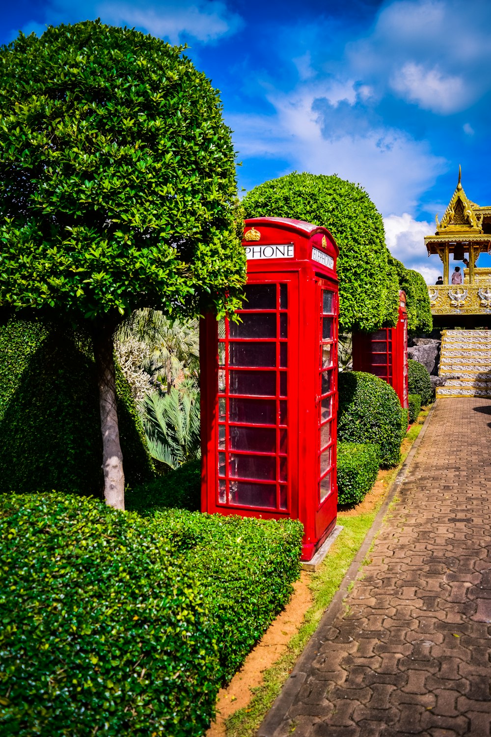 a red phone booth sitting in the middle of a garden