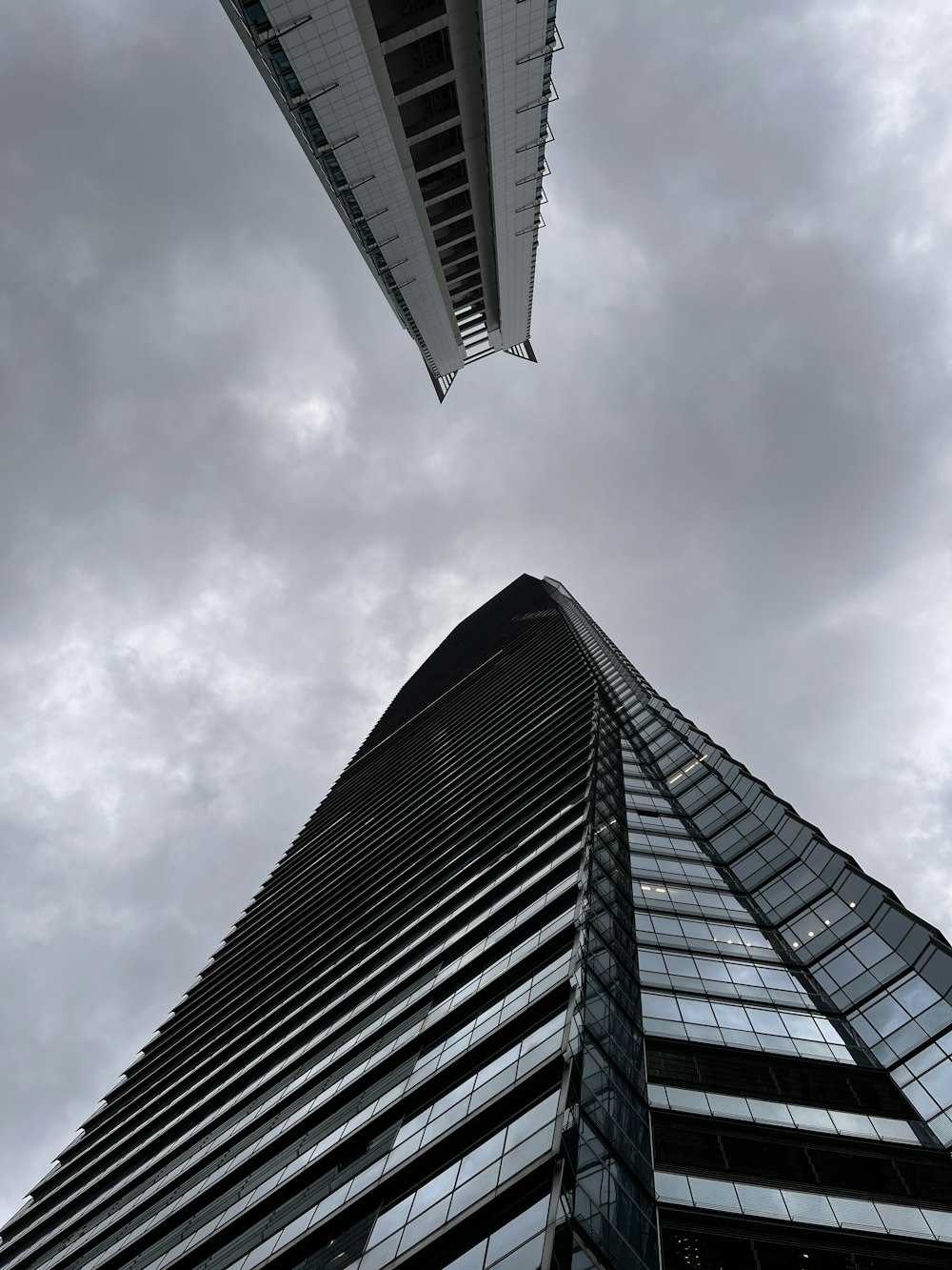 looking up at a tall skyscraper in a cloudy sky