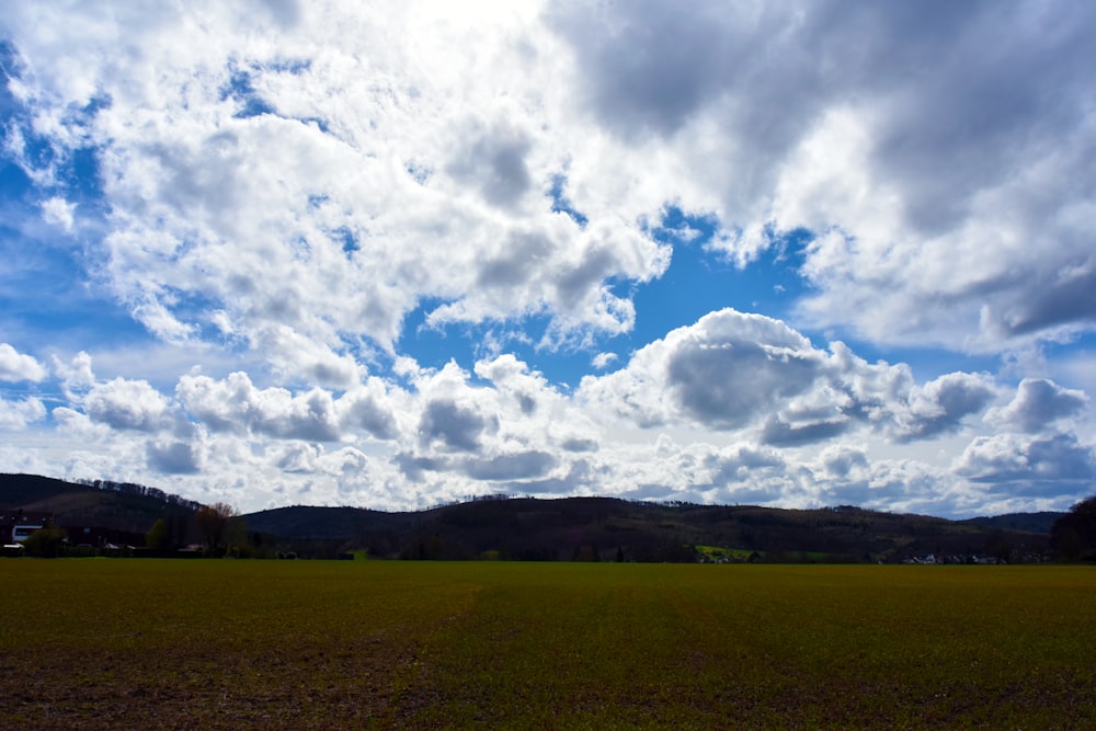 a large open field with some clouds in the sky