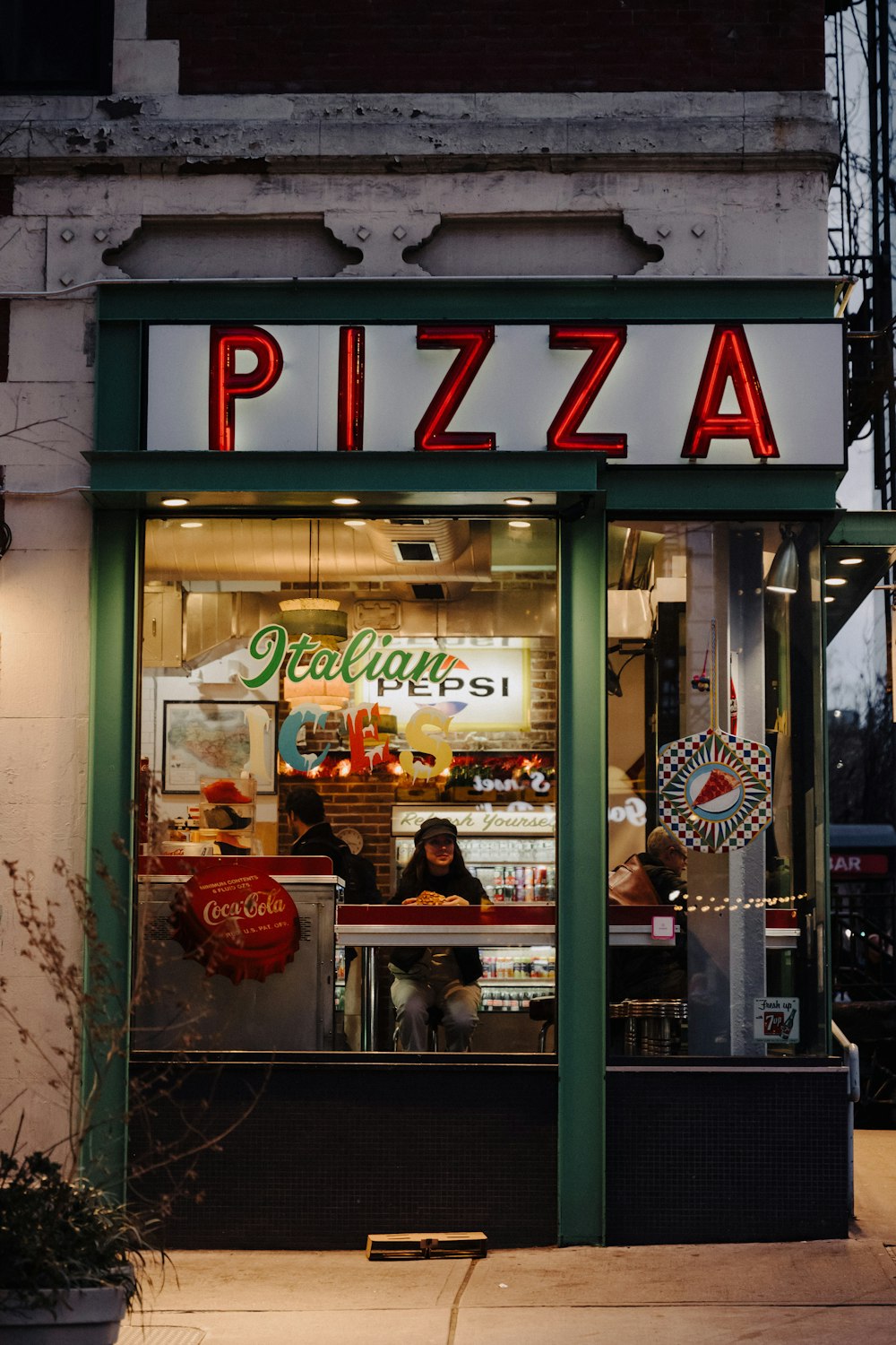 a pizza shop is lit up at night