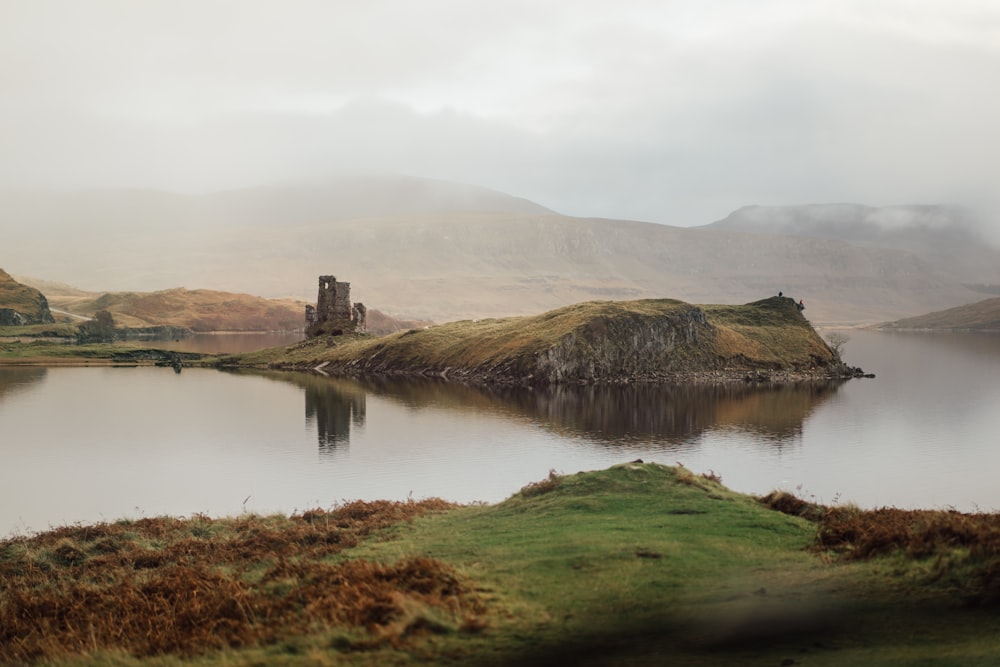 a lake surrounded by mountains with a castle in the middle