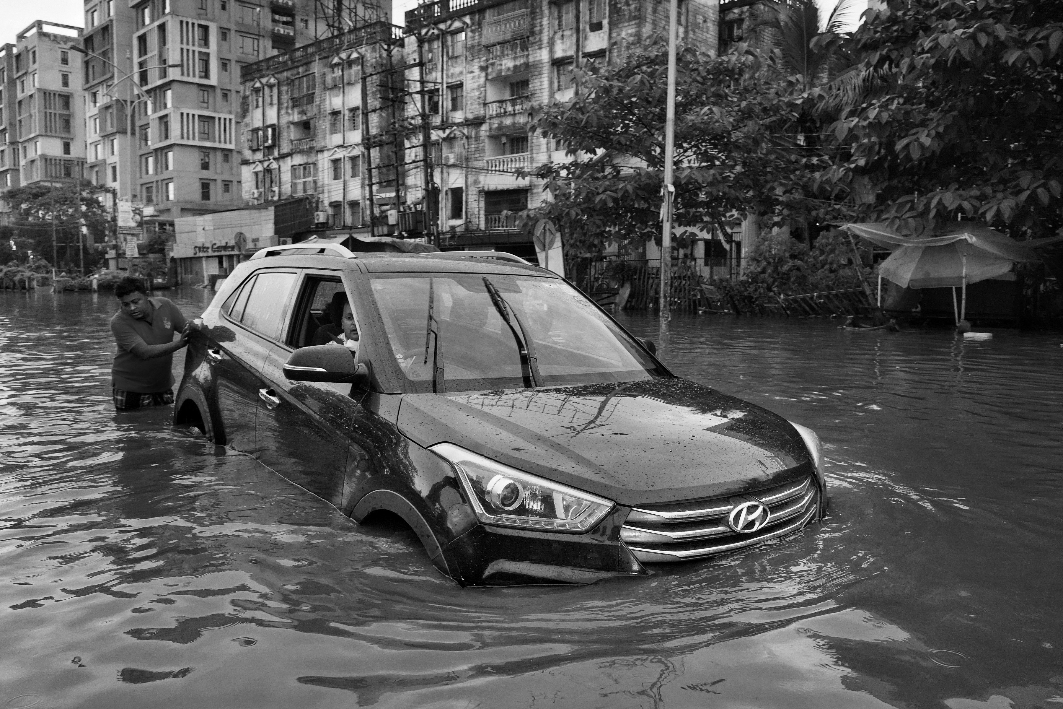 a black and white photo of a car in a flooded street
