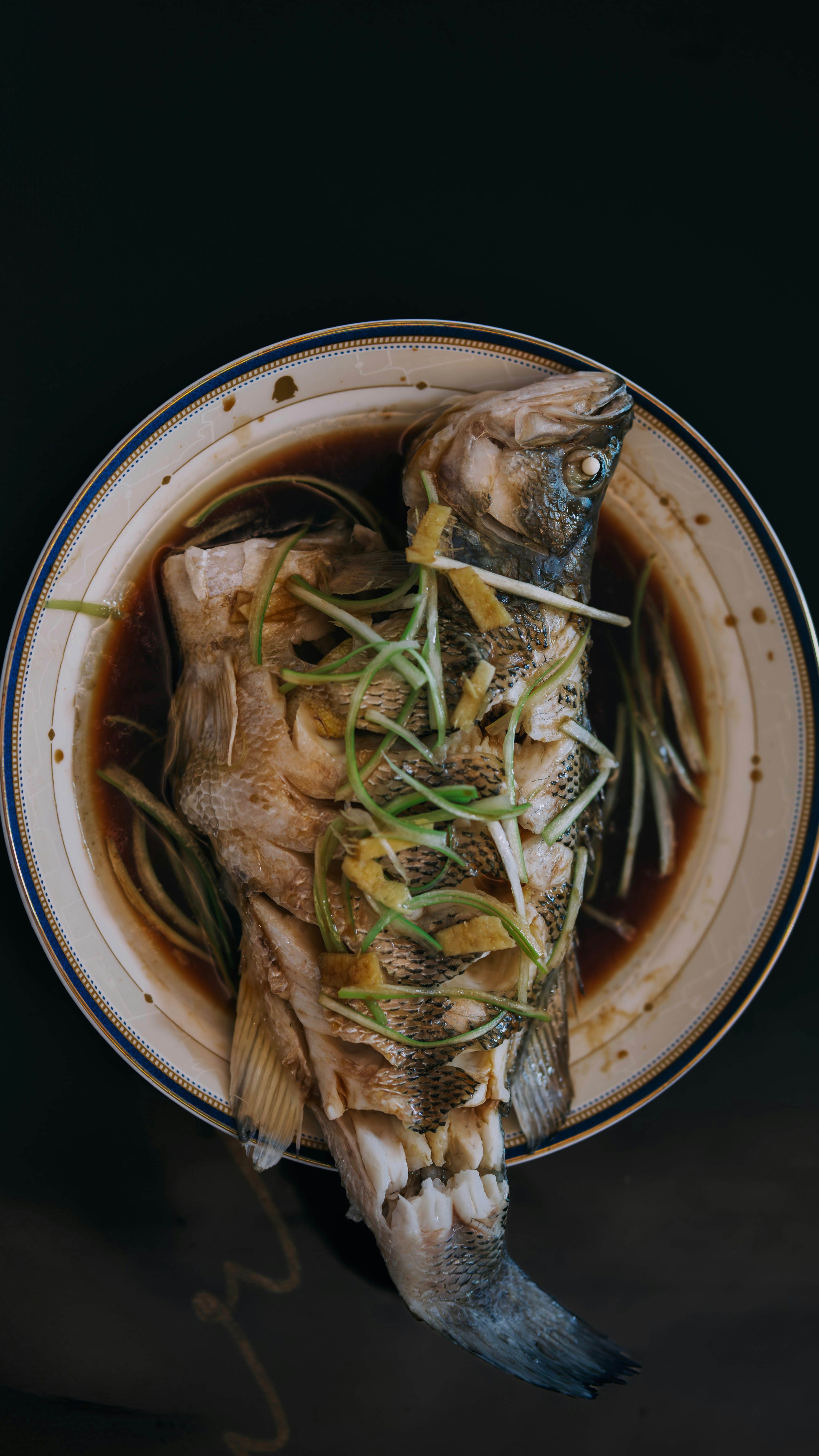 Рыба на пару с имбирем — authentic Chinese dish, professionally plated, dark moody background, commercial food photography