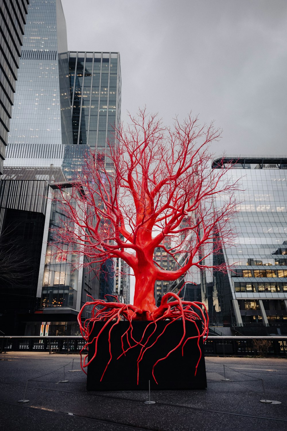 a sculpture of a red tree in a city square