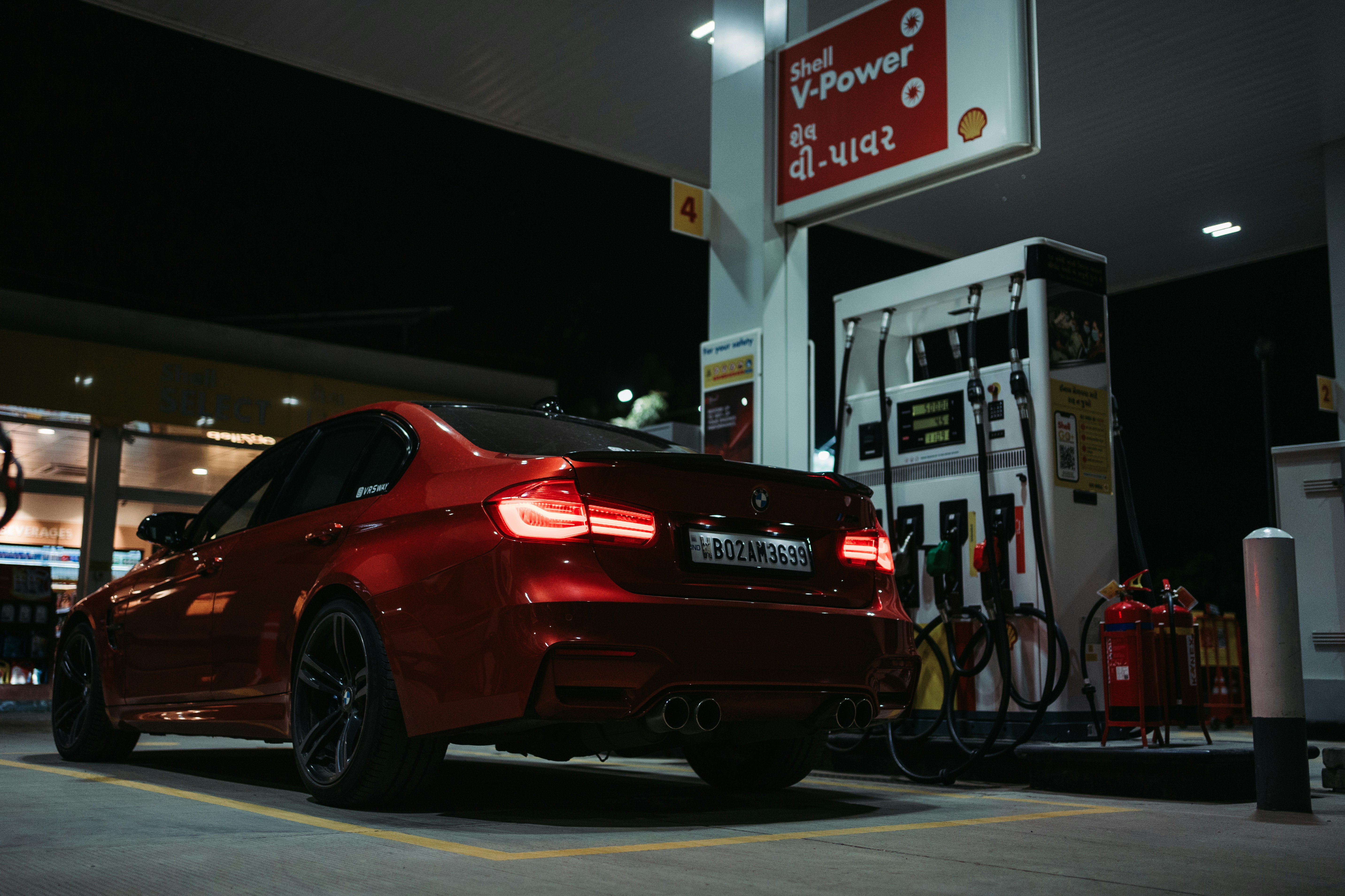 Sebuah mobil merah diparkir di depan pompa bensin