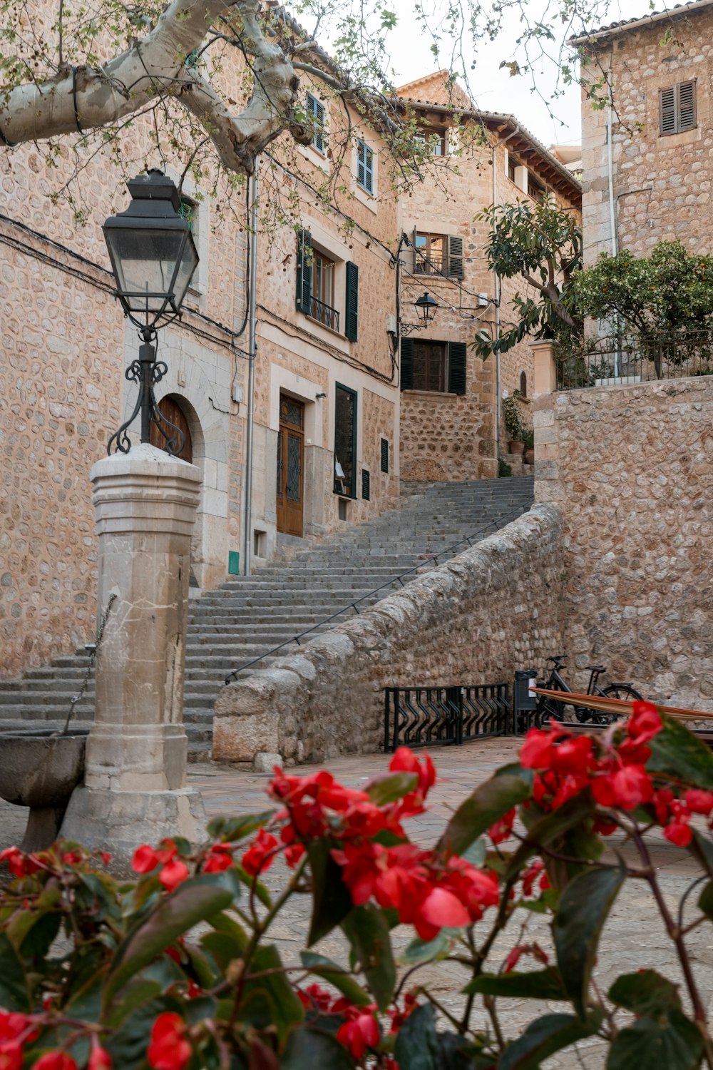 a stone building with a lamp post and flowers in front of it