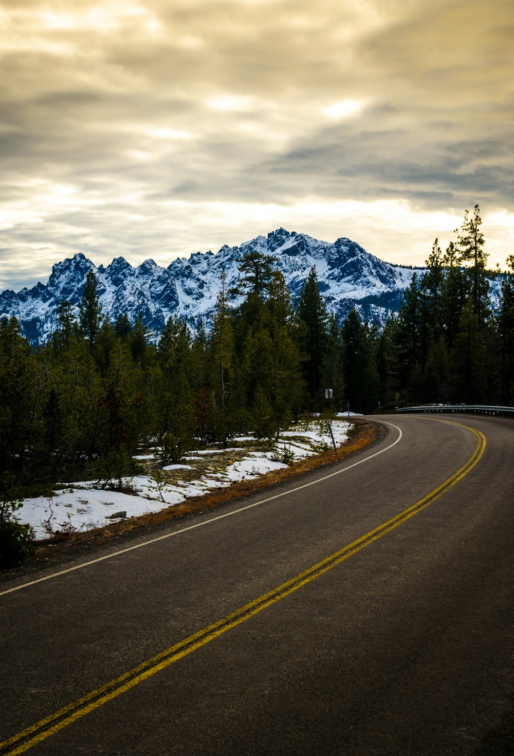 a winding road with snow covered mountains in the background