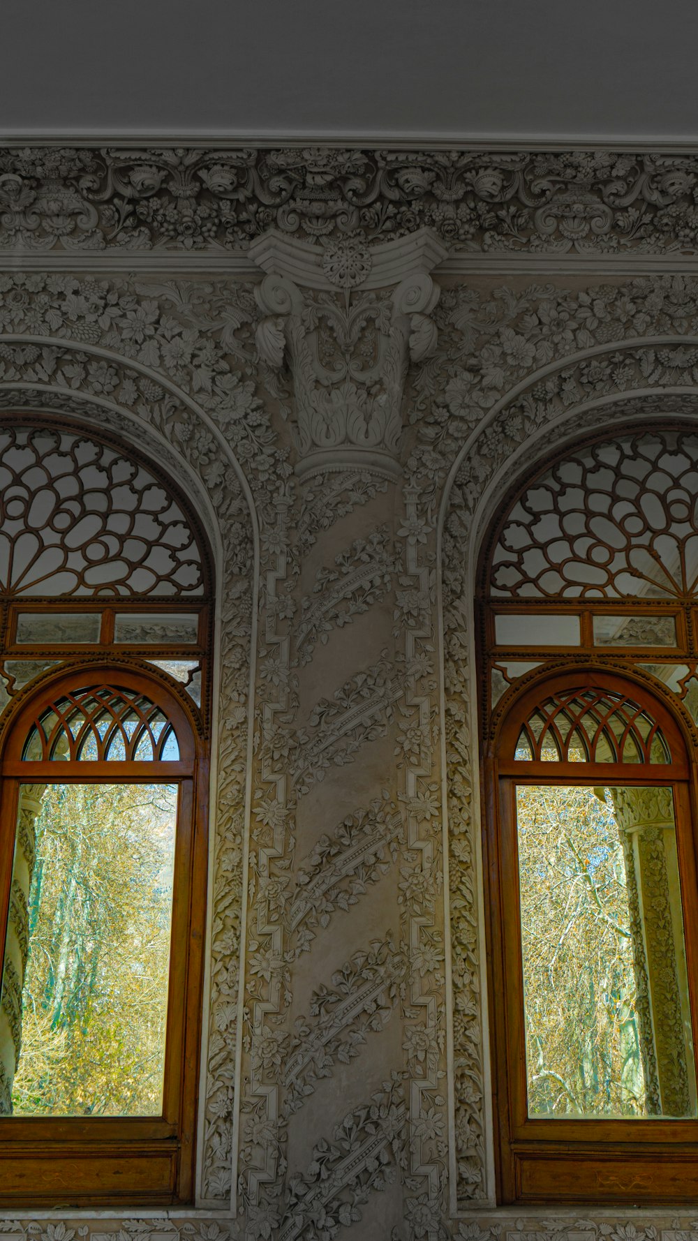 two windows in a wall with a tree in the background