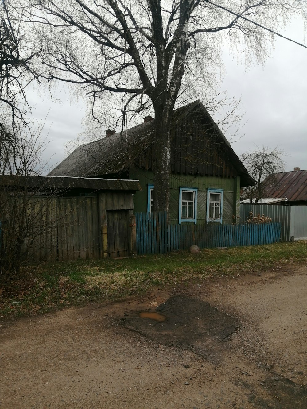 a dirt road next to a green house