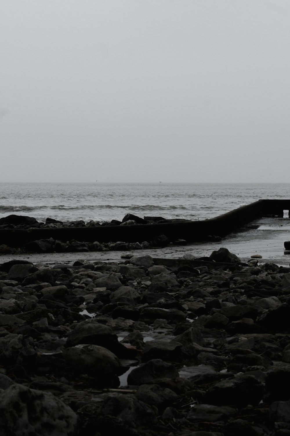 a black and white photo of a person walking on a rocky beach