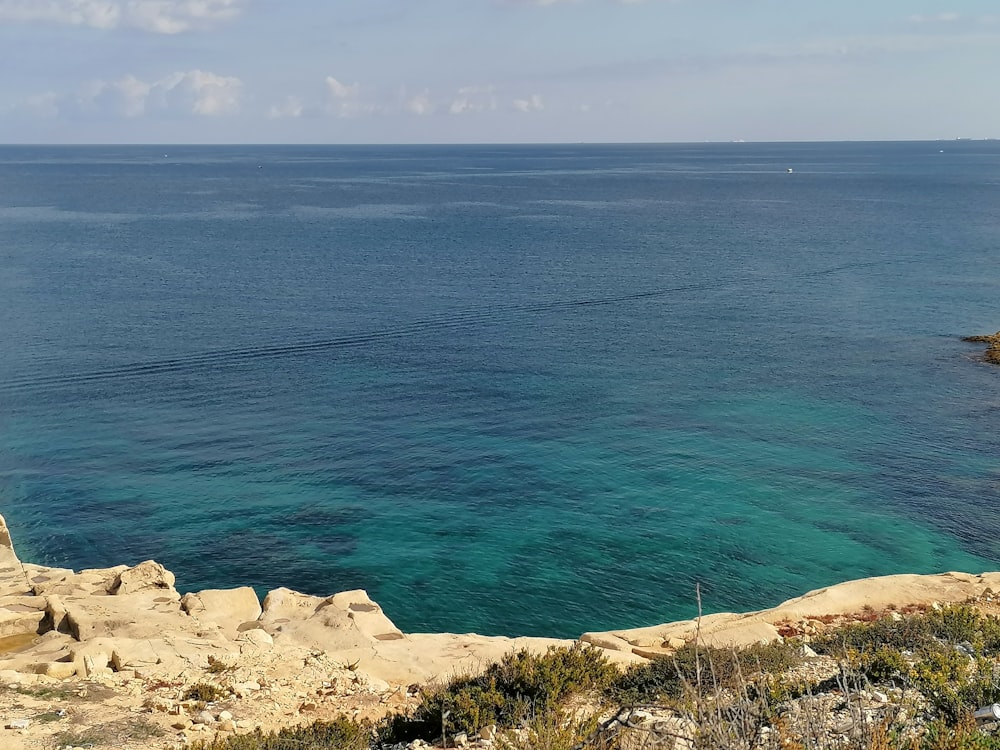 a large body of water sitting next to a lush green hillside