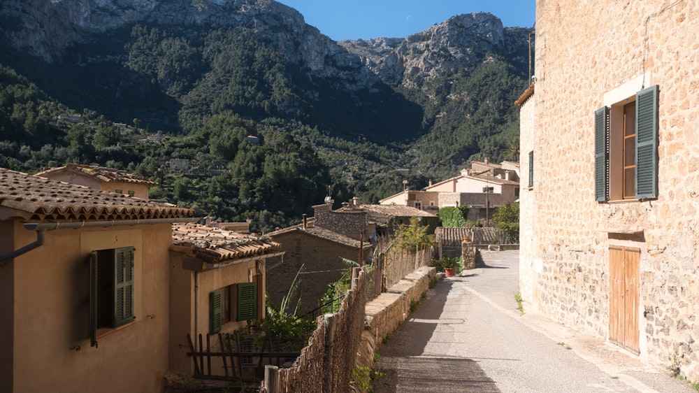 a narrow street in a small village with mountains in the background