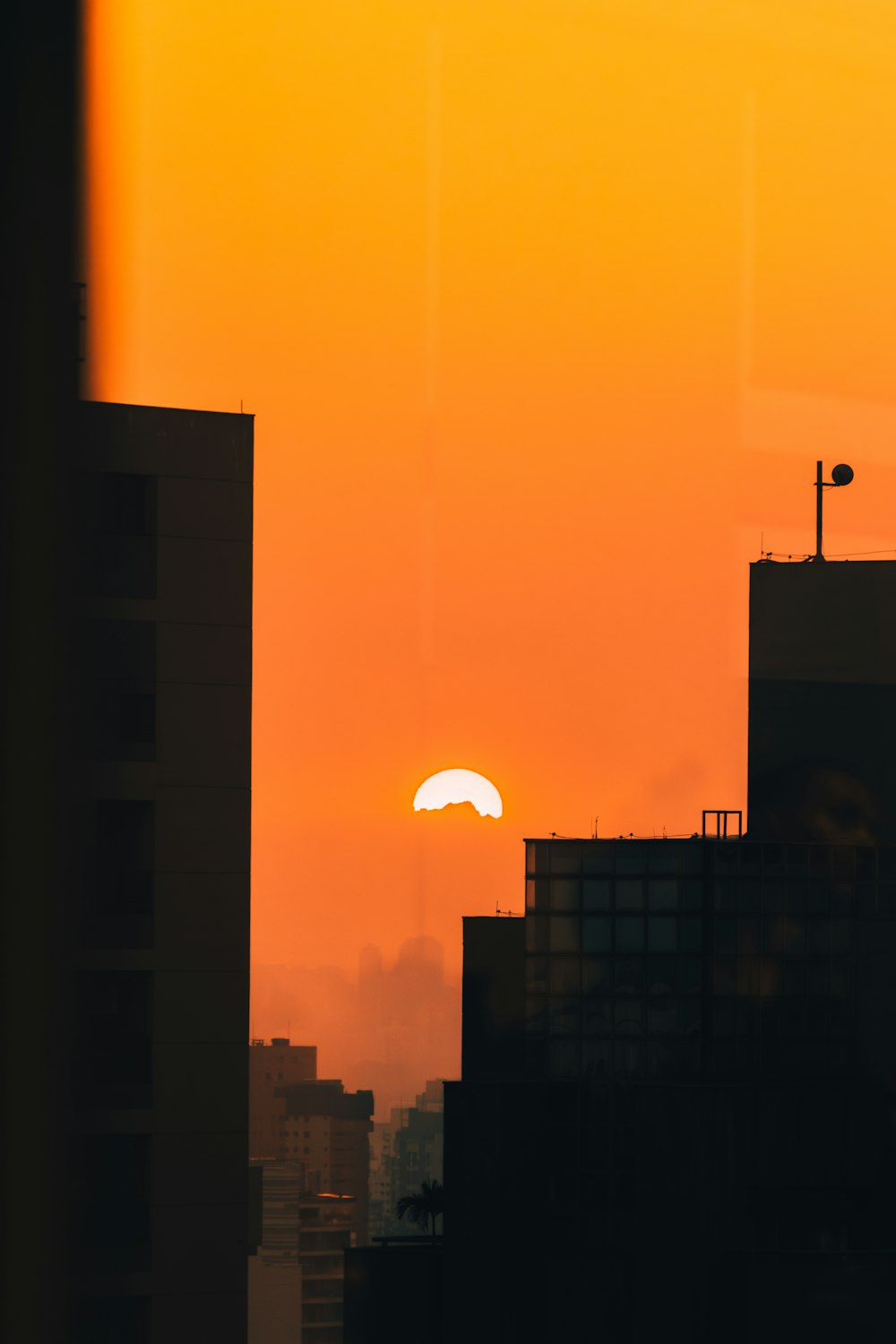 the sun is setting over a city with tall buildings