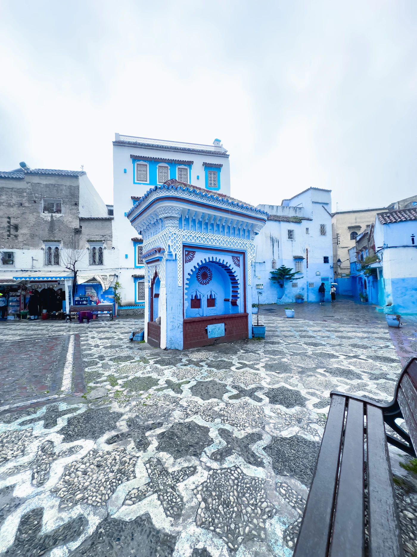 A blue and white fountain in a square of the old town