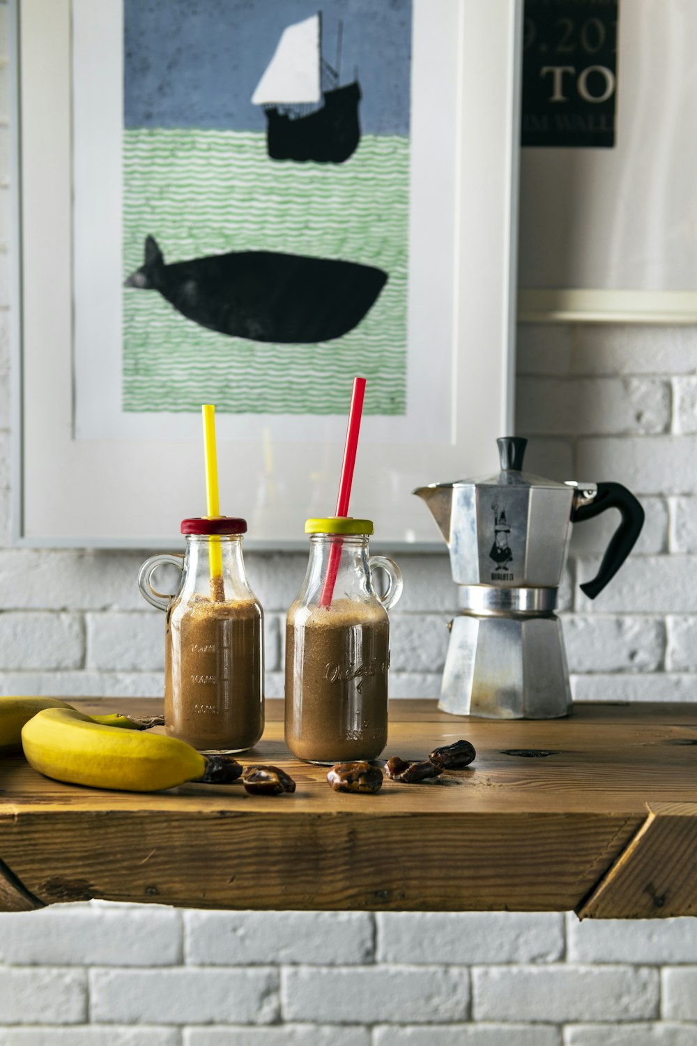 two glasses of coffee sit on a table next to a banana