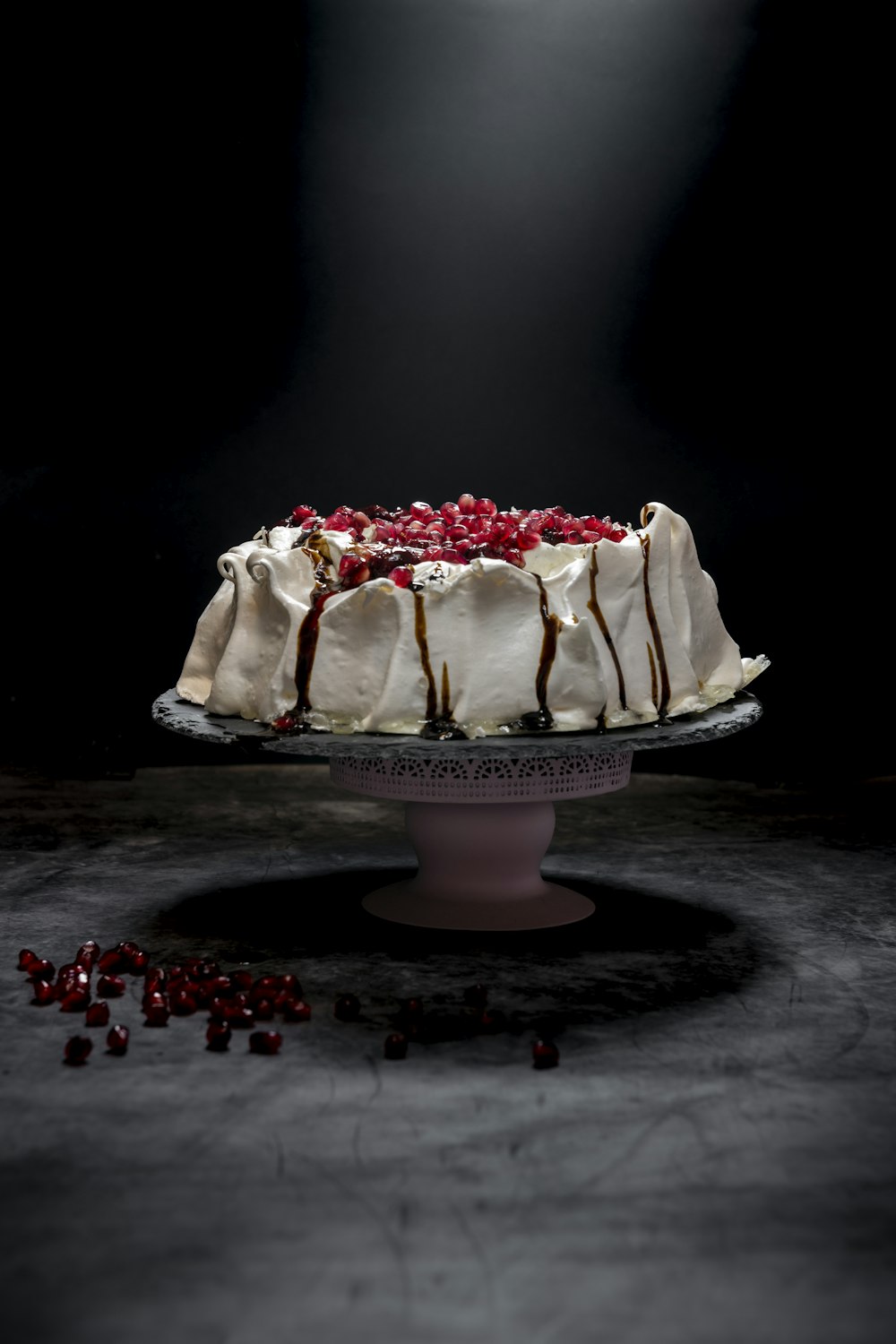 um bolo com cobertura branca e cranberries em um prato