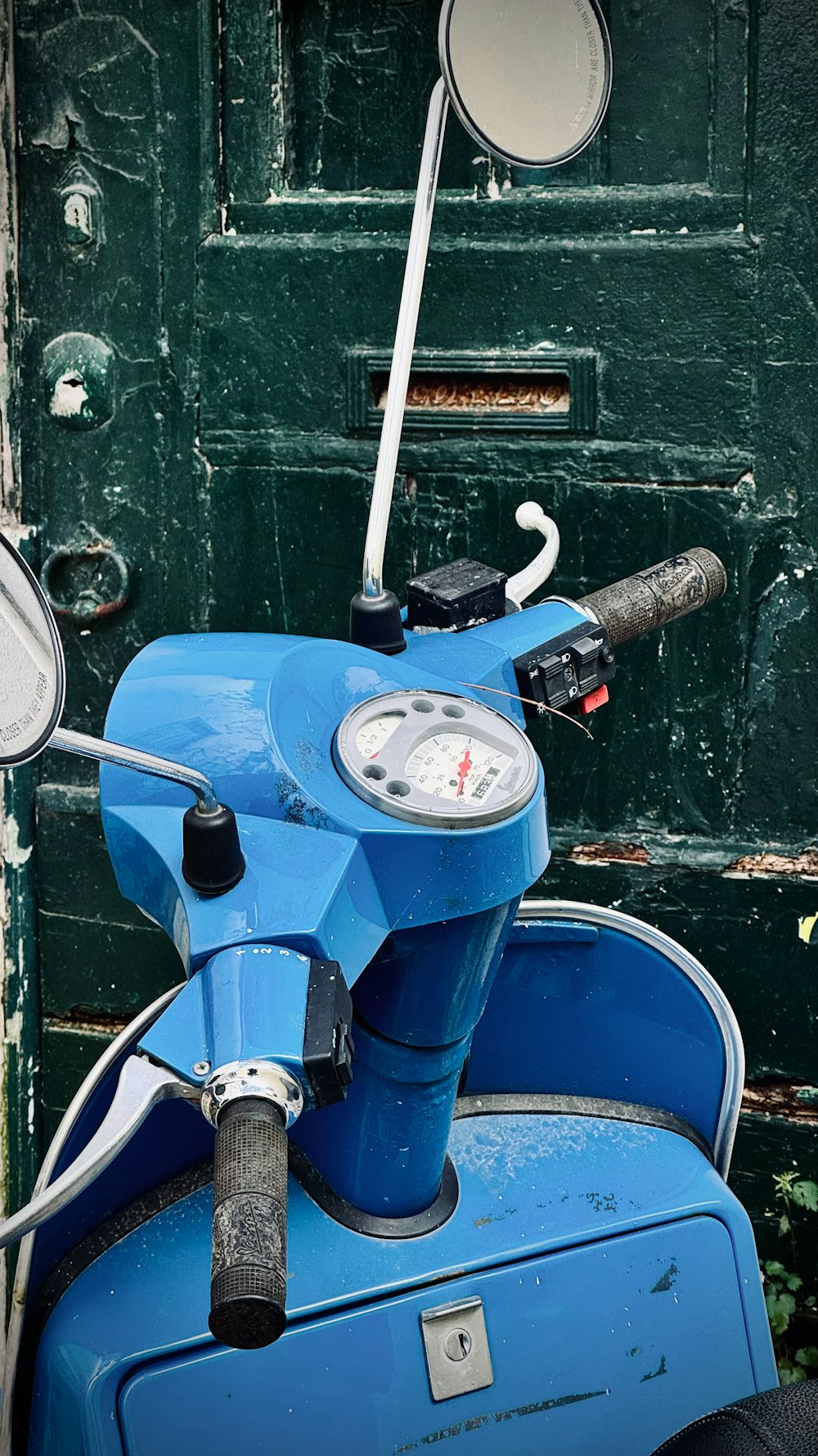 a blue scooter parked in front of a green door