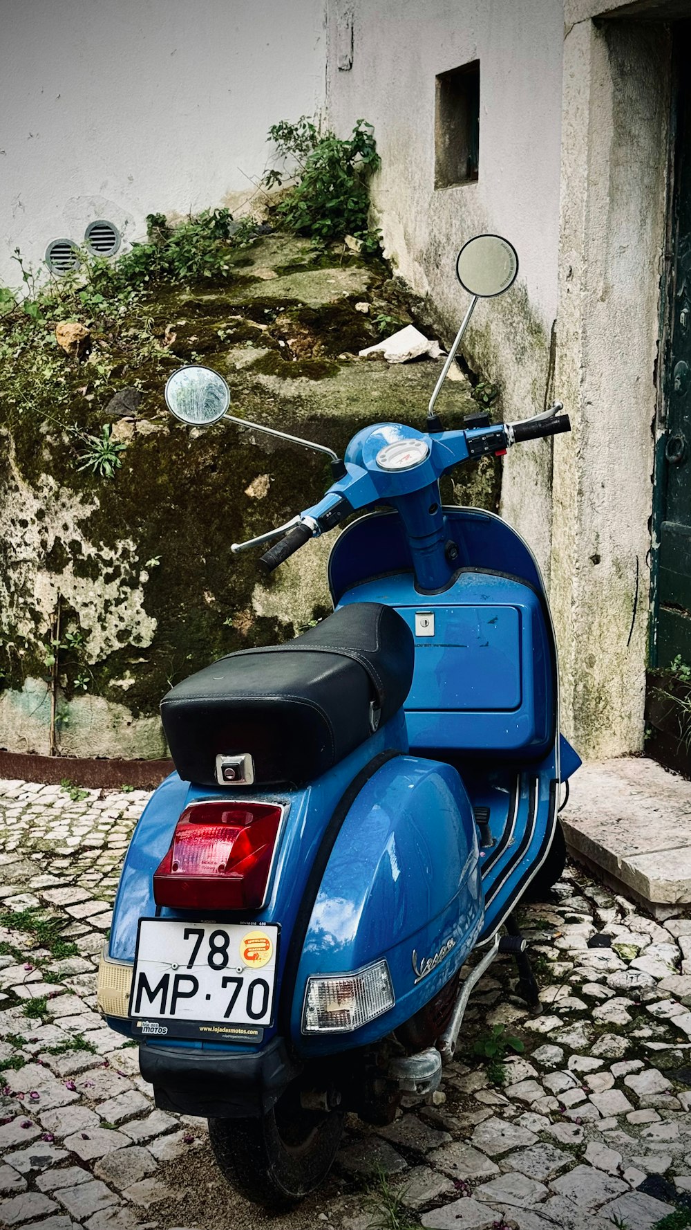 a blue scooter parked on a cobblestone street
