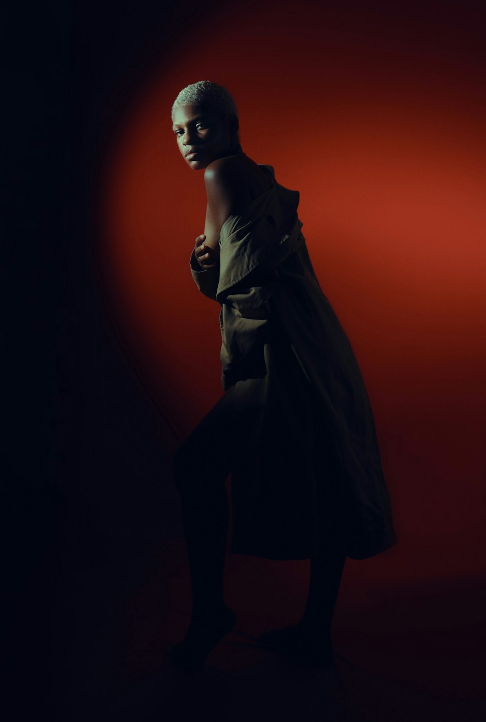 a woman in a trench coat standing in a dark room