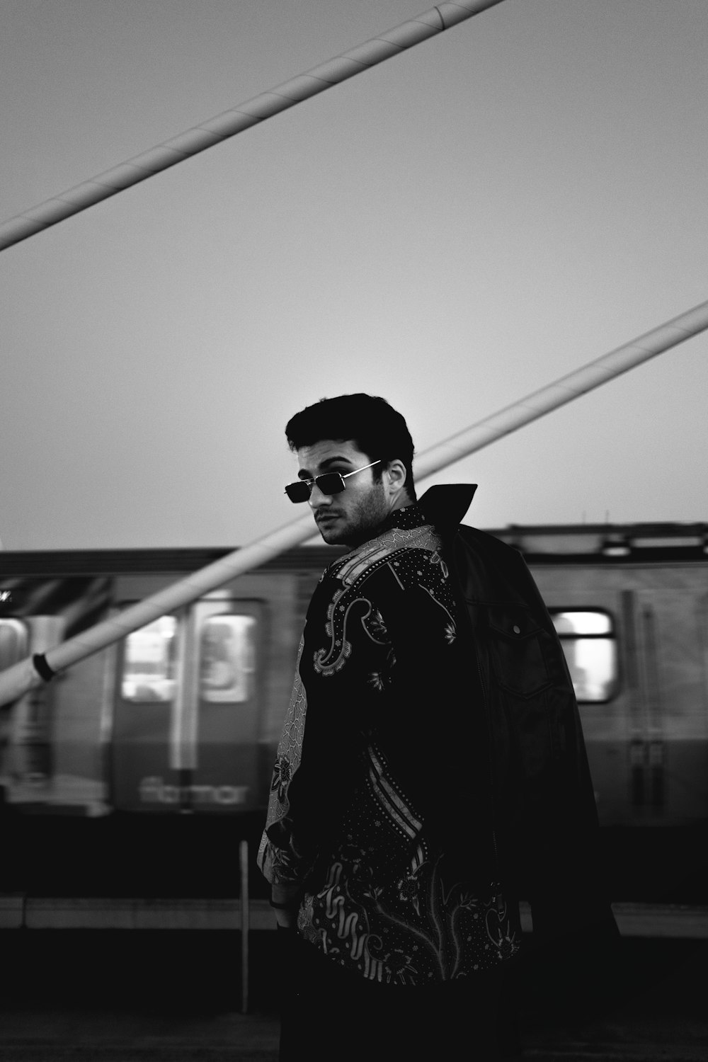 a man with sunglasses standing in front of a train