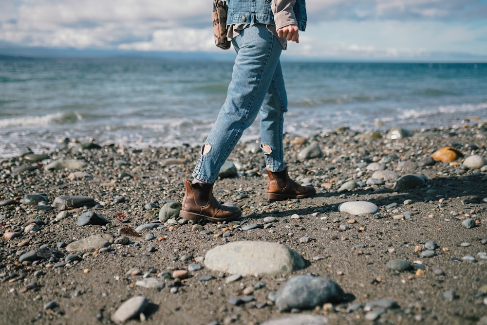 a person standing on a rocky beach next to the ocean