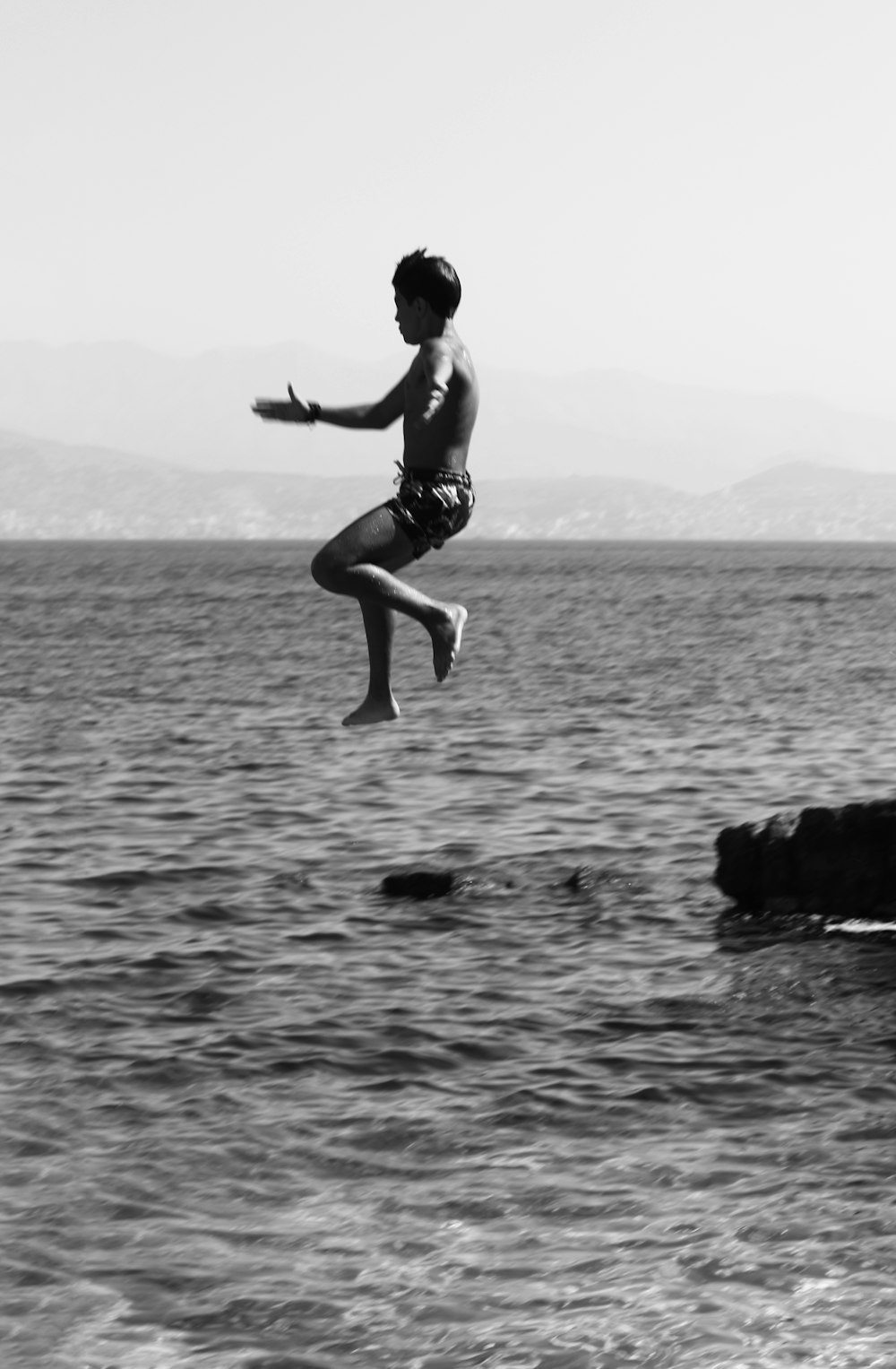 a person jumping into the water from a cliff