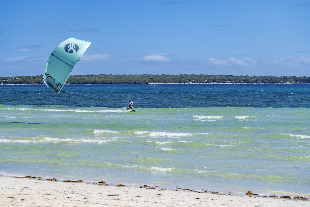 a person windsurfing in the ocean on a sunny day