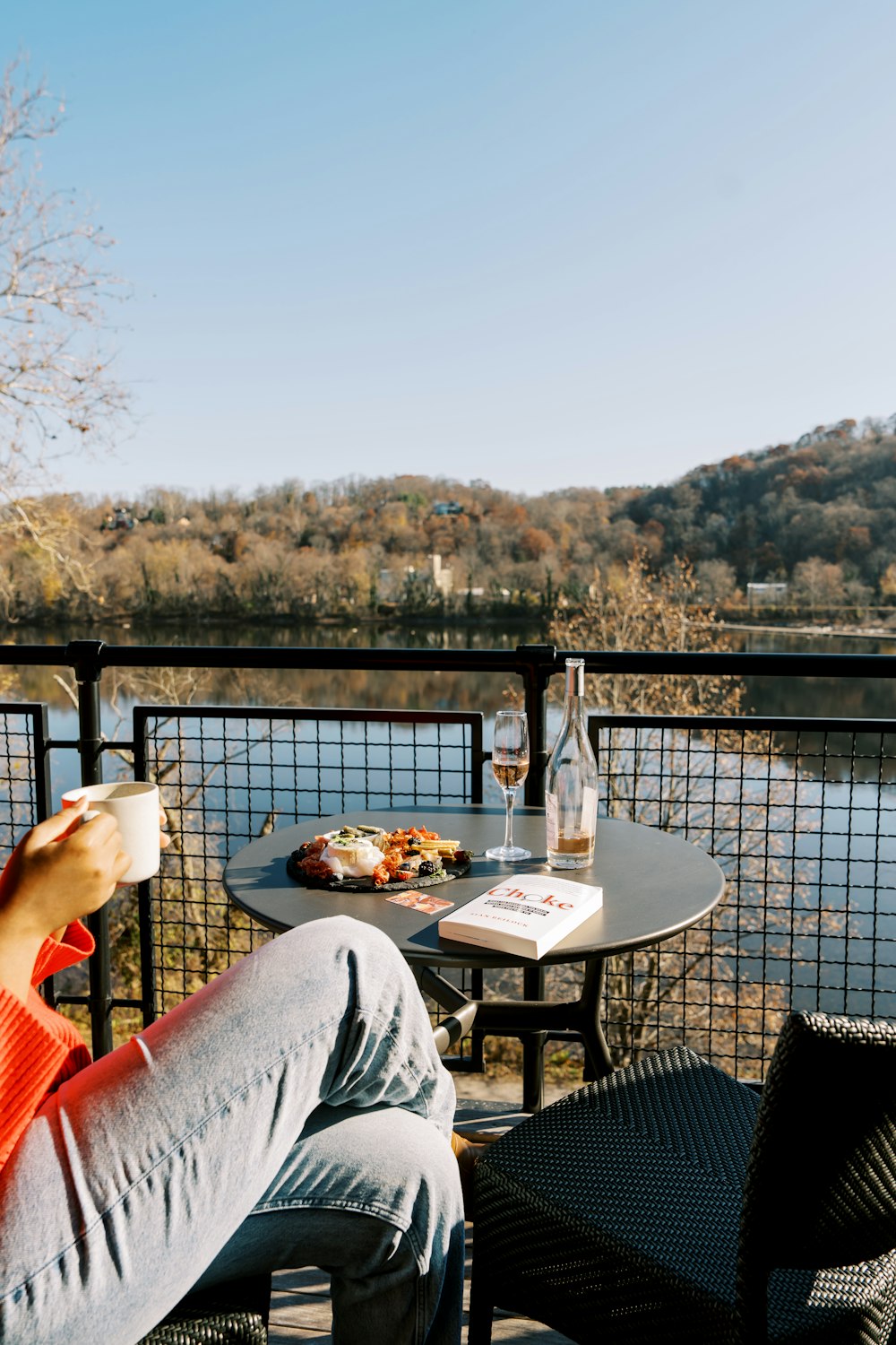 a person sitting at a table with a book and a drink