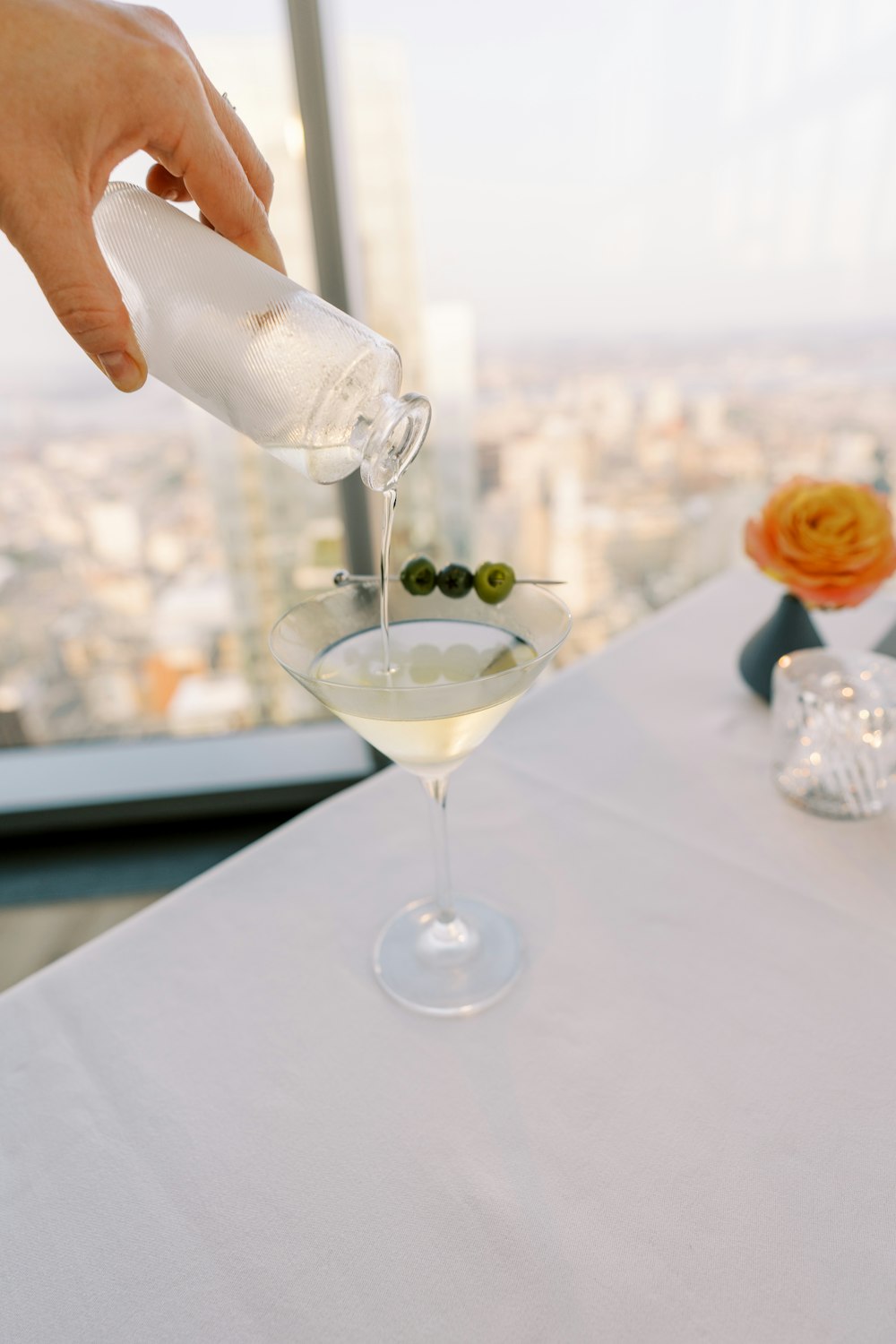 a person pours a drink into a martini glass