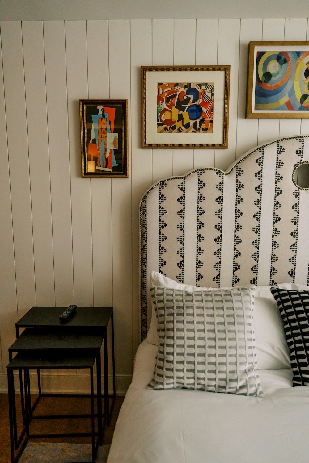 a bed with a white headboard and black and white pillows