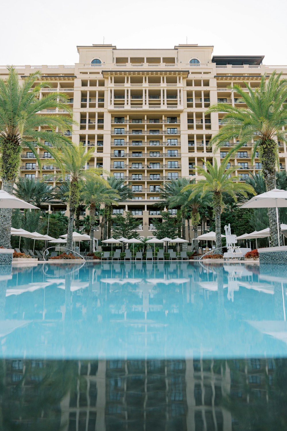a large hotel with a pool surrounded by palm trees