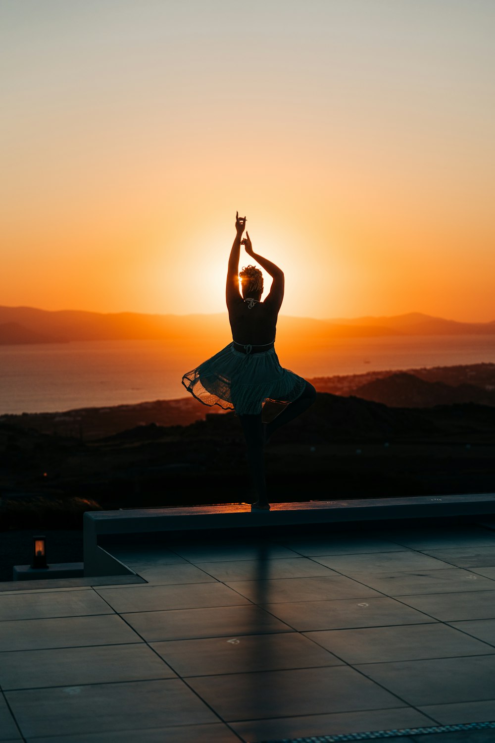 Una persona haciendo una postura de yoga frente a una puesta de sol