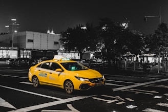 a yellow taxi cab driving down a street at night