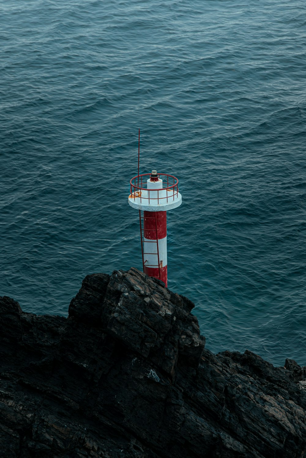 a red and white lighthouse sitting on top of a cliff