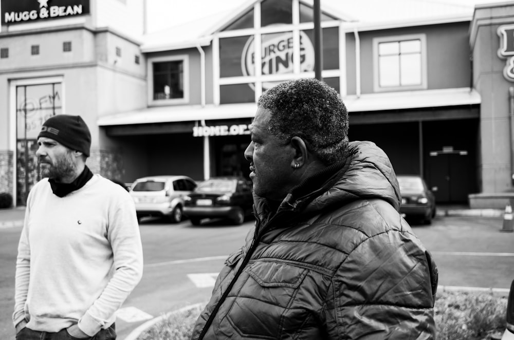 a black and white photo of two men standing in front of a building