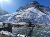 a snow covered mountain with a bridge over a river