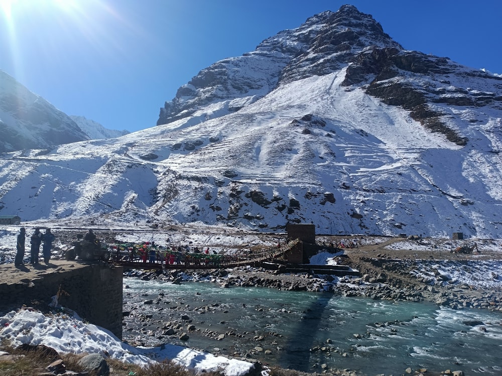 uma montanha coberta de neve com uma ponte sobre um rio